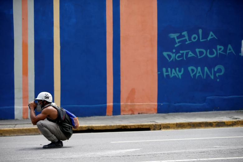 A demonstrator is seen near a graffiti that reads 