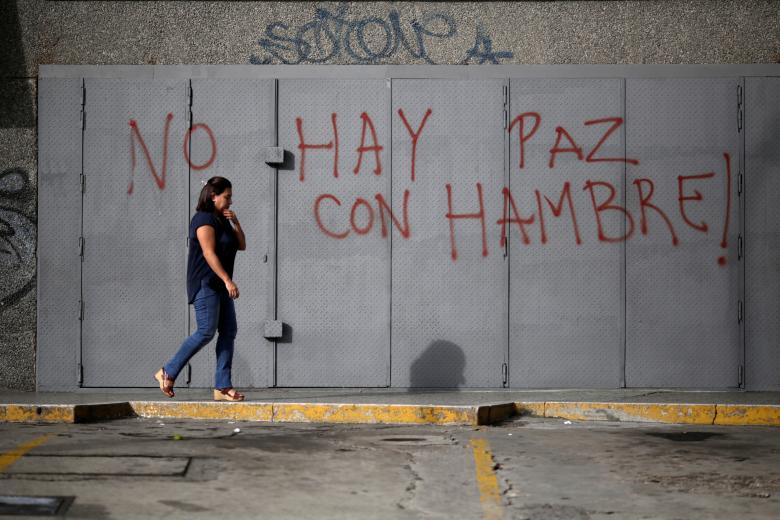A woman walks in front of a graffiti that reads 