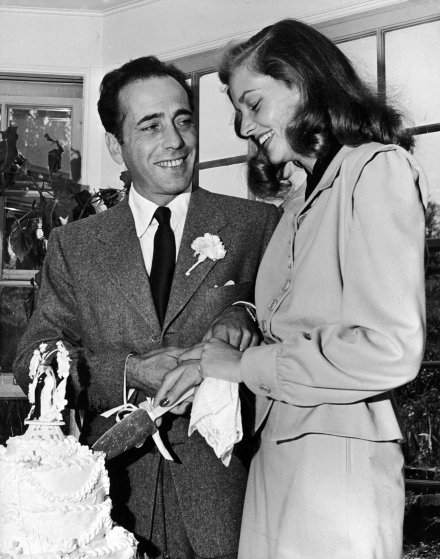 Actor Humphery Bogart helping his actress bride Lauren Bacall cut wedding cake at their wedding reception held at novelist Louis Bromfield