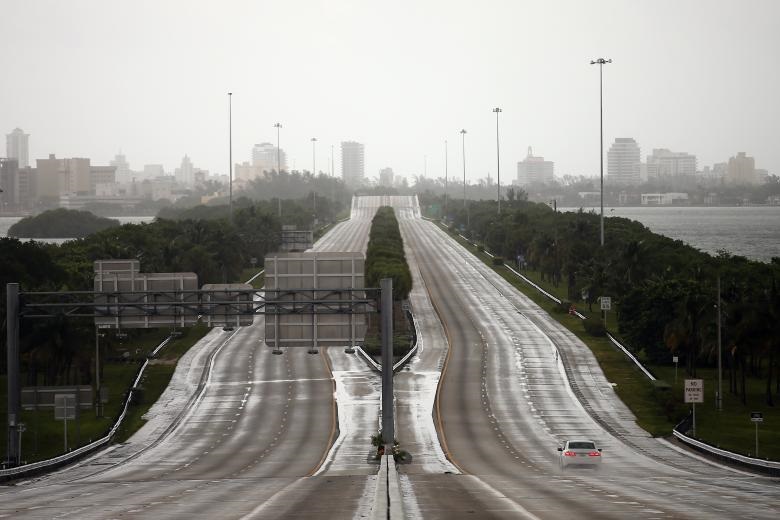A car drives along an empty highway in Miami. REUTERS/Carlos Barria