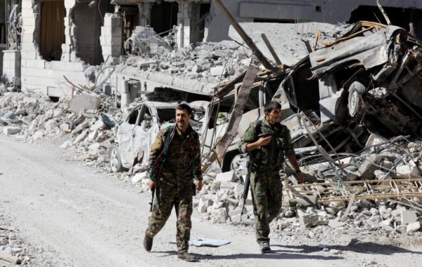 Fighters of Syrian Democratic Forces walk along a road past destroyed vehicles at the frontline. REUTERS/Erik De Castro