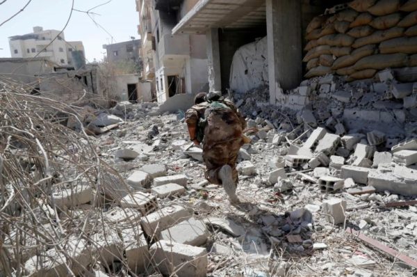 A member of Syrian Democratic Forces runs for cover from the sniper fire of the Islamic State militants near the stadium. REUTERS/Erik De Castro